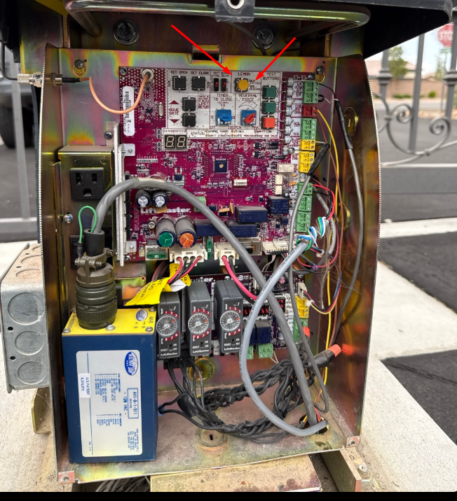 Gate control box — red arrows pointing to the yellow LEARN button